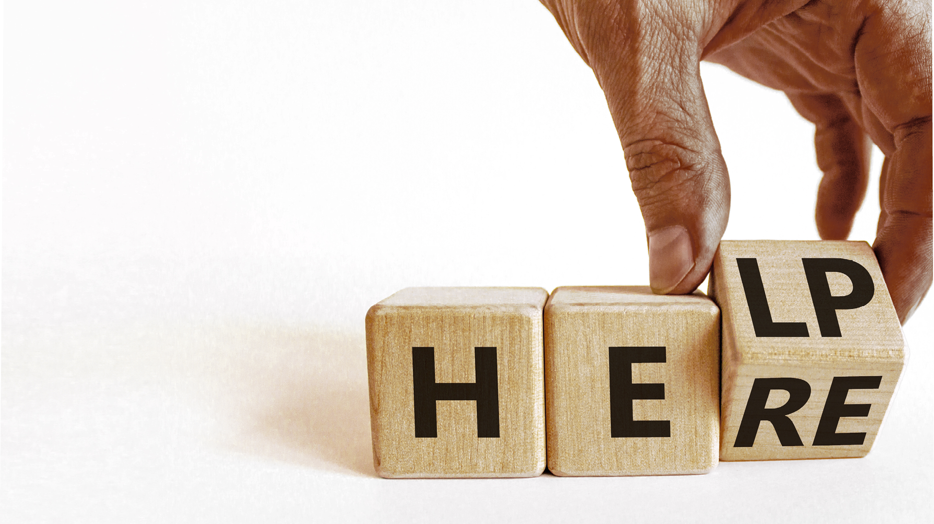 Help is here support symbol. Businessman turns the wooden cube and changes the concept word Help to Here. Beautiful white table white background, copy space. Business support help is here concept.